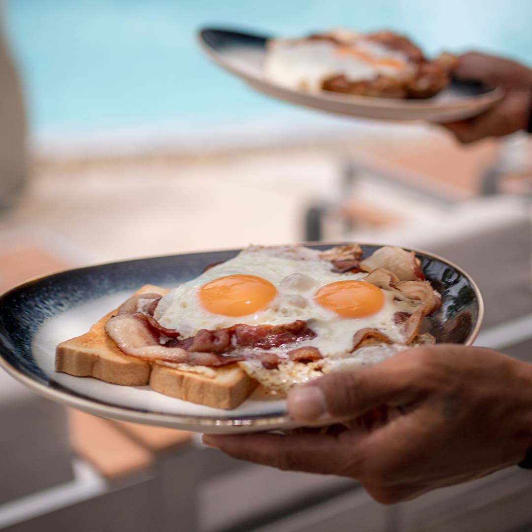 Two plates of eggs and bacon on toast served poolside at ARKbar Beach Club, Chaweng Beach