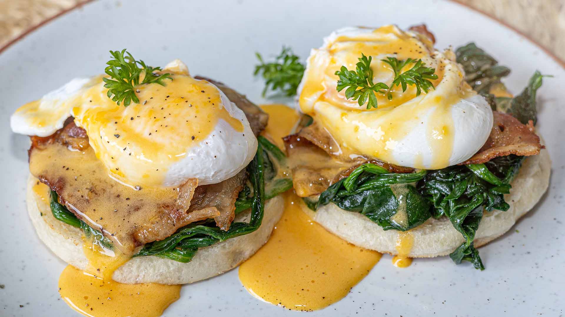 Poached eggs with hollandaise sauce on English muffins, served with sautéed spinach and crispy bacon – a signature breakfast at HIP Restaurant in Chaweng, Koh Samui.
