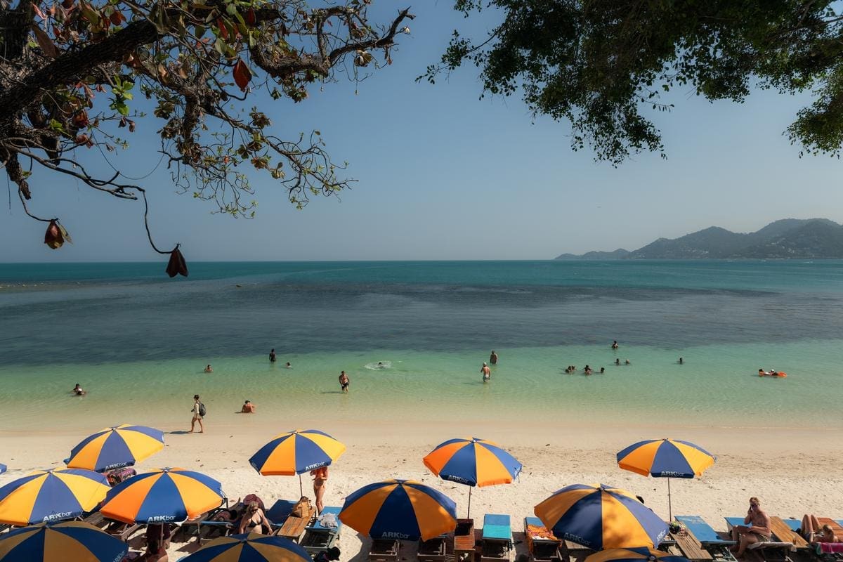 Chaweng Beach Koh Samui clear water swimmers and ARKbar beach club umbrellas with mountain backdrop